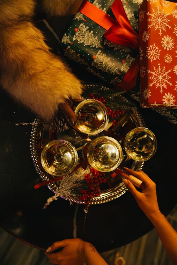 Guests raising champagne glasses over festive gifts and elegant decorations during an upscale holiday party at SideBar San Diego.