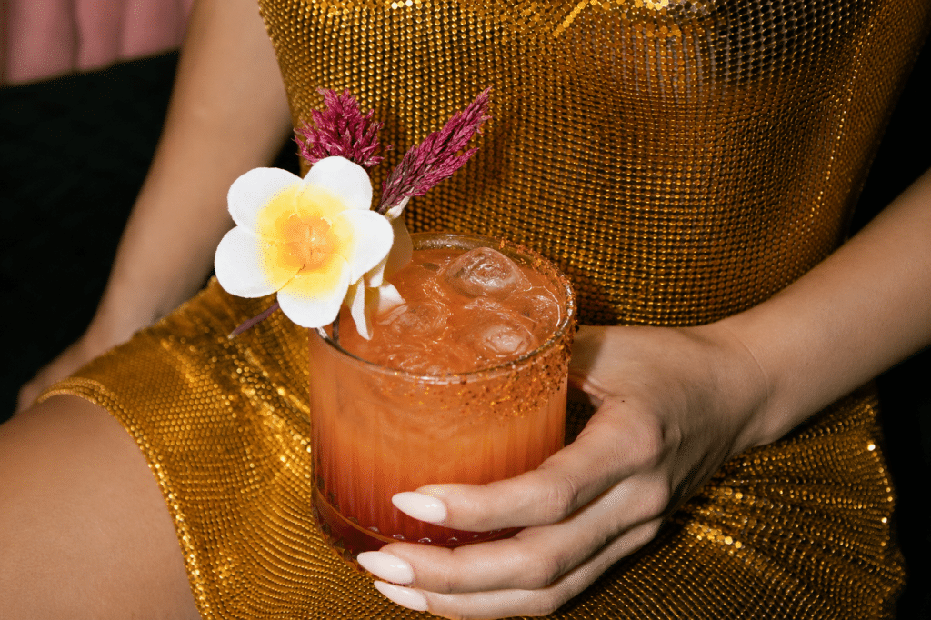Guest holding a signature cocktail with floral garnish during an upscale client mixer event in a stylish lounge.
